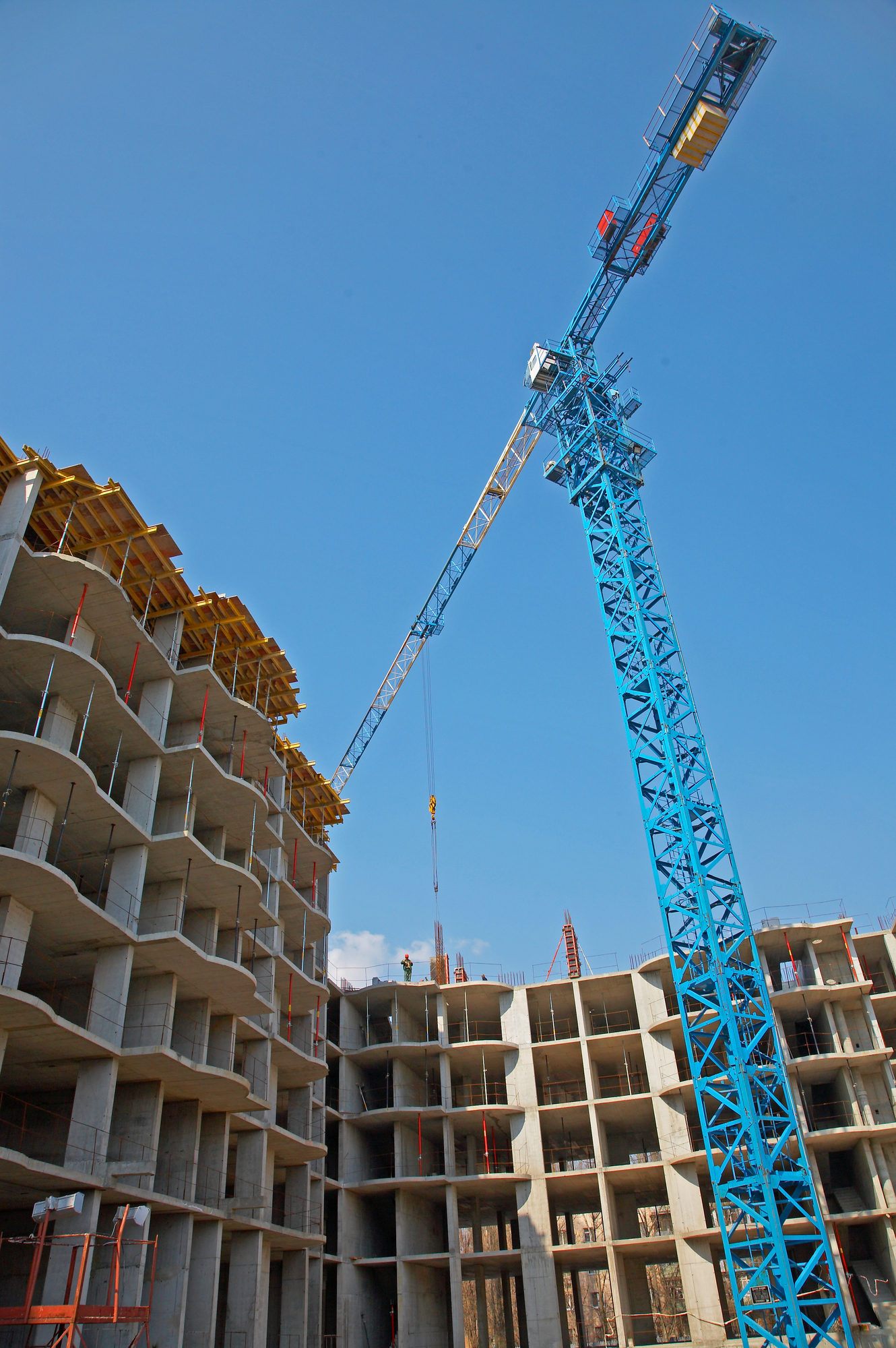 Wohn-und-Gewerbebauprojekte – Es ist ein Kran vor einem halbfertigen Gebäude zu sehen.